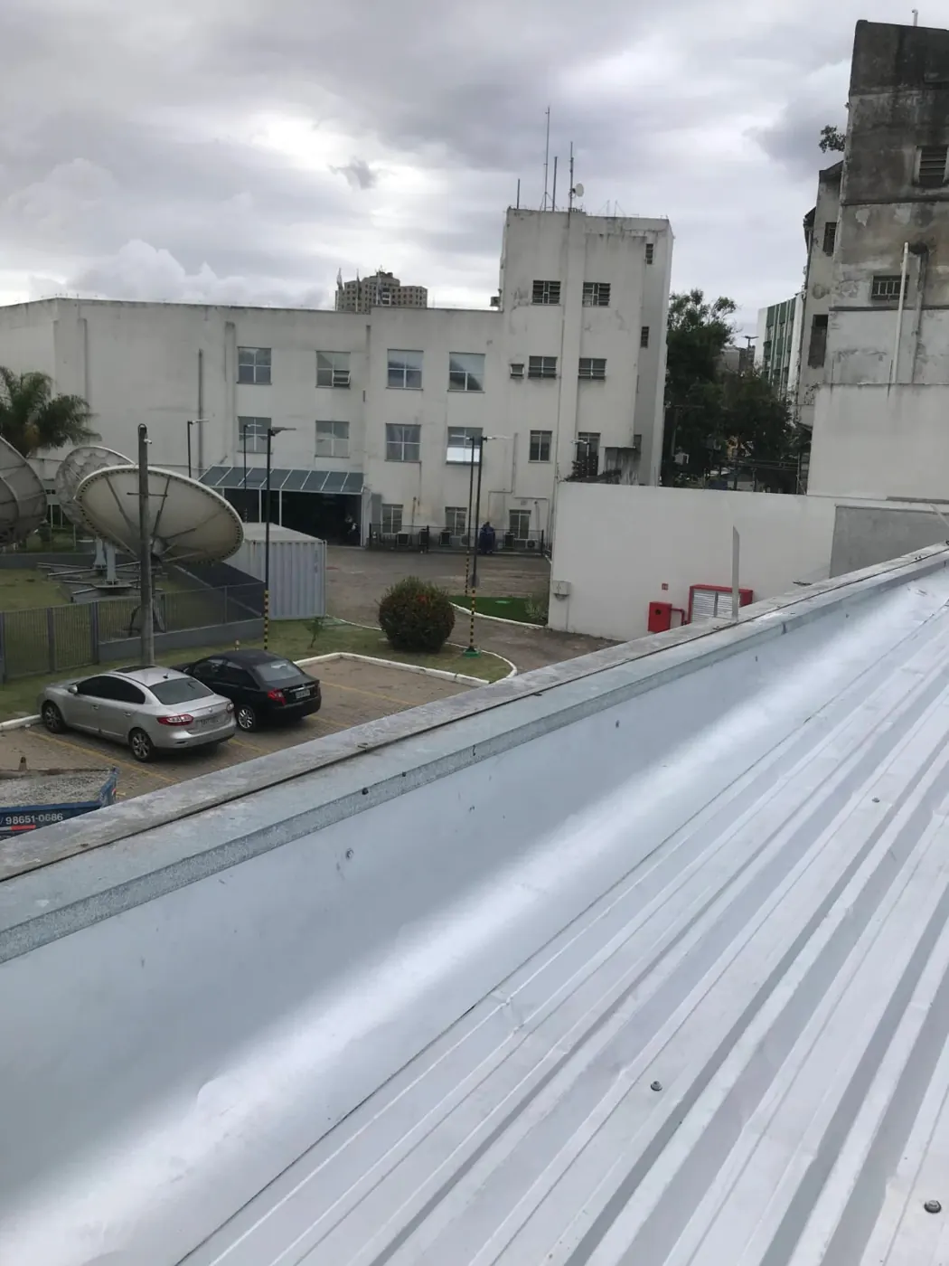 Cobertura metálica vista de cima, com o estacionamento ao lado